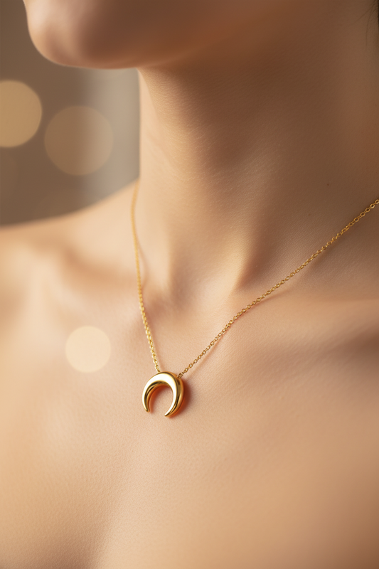 Gold crescent moon necklace on a womans neckline