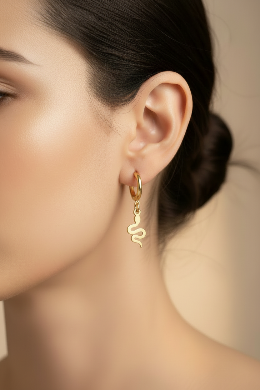 womans side profile wearing the Mini Snake Drop Huggie Earrings in gold with dark hair and warm background