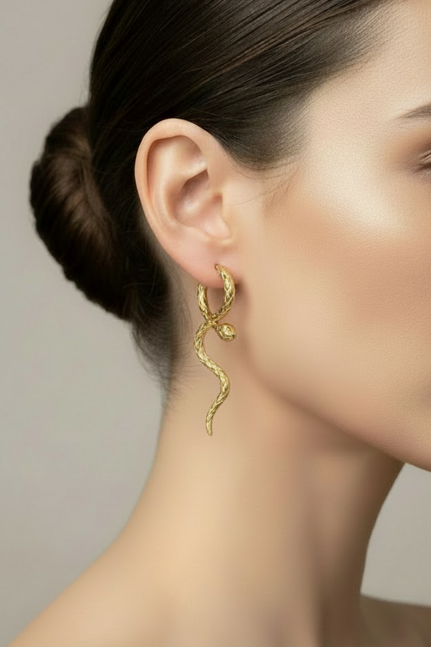 womans side profile wearing the gold  Snake Loop Through Earrings, with dark hair and plain background