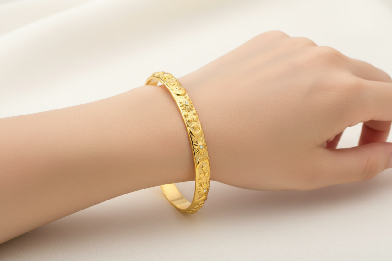 womans wrist wearing Gold bracelet with engraved design on a white background