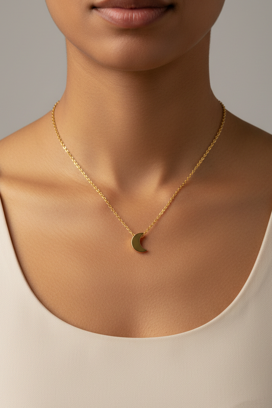 womans neckline wearing the gold mini crescent moon necklace in a white tshirt on a white background